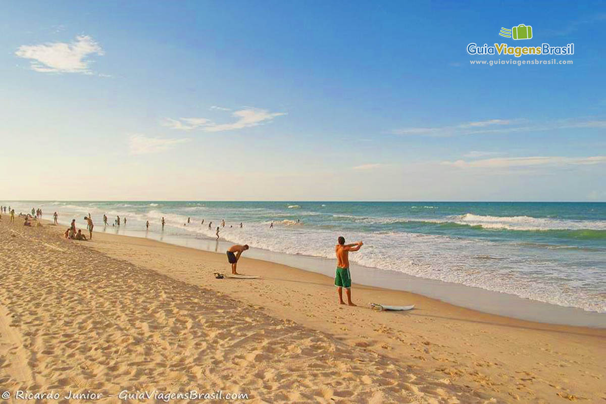 Imagem de dois surfistas nas areias se aquecendo nas areias da praia.